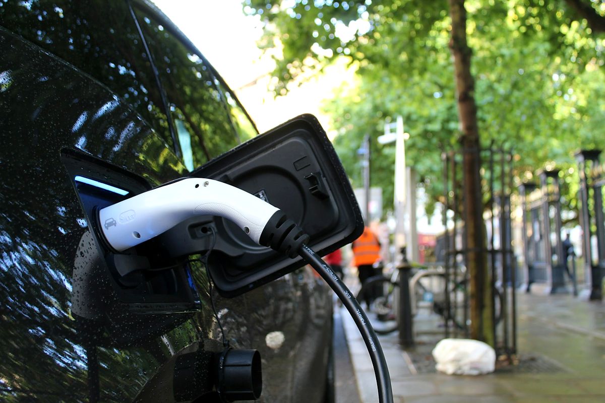 Veículo elétrico conectado a ponto de recarga em via pública
