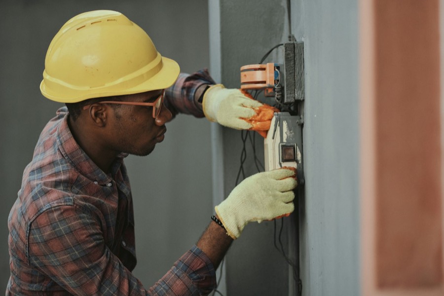 Eletricista com capacete instalando fiação